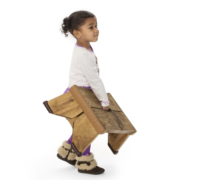 Child carrying outlast bench in outdoor play and learning.